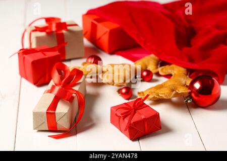 Sac Santa avec boules de Noël, boîtes cadeaux et cornes de renne sur fond de bois blanc Banque D'Images