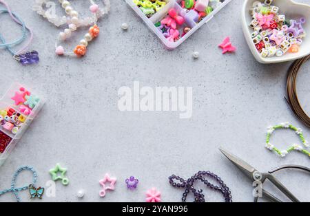 L'activité de fabrication de perles montre diverses perles colorées et des outils étalés sur une surface grise, parfait pour créer des pièces de bijoux uniques dans l'après-midi Li Banque D'Images