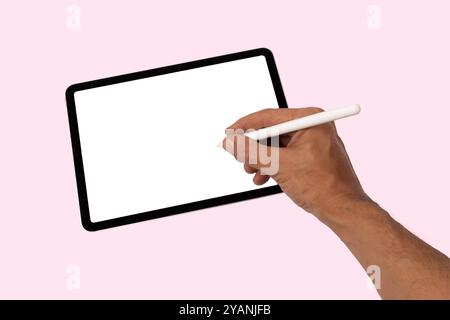 Dessin à la main masculine ou écriture sur un écran blanc de tablette avec fond rose de crayon intelligent Banque D'Images