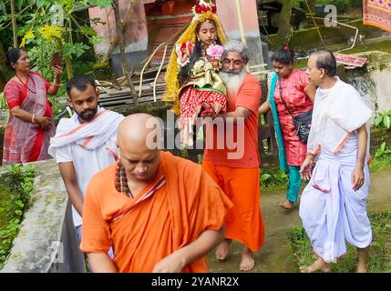 Les prêtres transportent Debalina Chakraborty, une fille hindoue âgée de neuf ans, cinq mois et quatorze jours, connue sous le nom de « Kumari », sur le site de Puja. Elle bâille en attendant le culte de prêtres hindous pendant Durga Puja à l'Ashram Ramakrishna Vivekananda. Kumari est vénéré dans le cadre des rituels de Durga Puja, qui est le plus grand événement religieux pour les hindous bengalis. Les hindous croient que la déesse Durga symbolise le pouvoir et le triomphe du bien sur le mal. Tripura, Inde. Banque D'Images