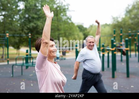 Heureux et en bonne santé. Couple de famille mature en vêtements de sport faisant de la gymnastique ensemble à la salle de gym extérieure Banque D'Images