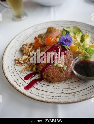 Hamburger végétalien gastronomique servi avec des noix, des légumes, des fleurs comestibles et une sauce à la betterave rouge vibrante Banque D'Images