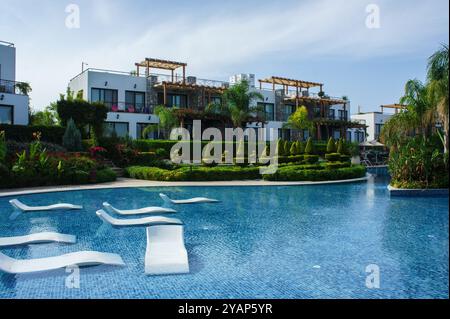 Dans un cadre de villégiature tranquille, les villas élégantes donnent sur une piscine étincelante, invitant à la détente. Les jardins luxuriants contribuent à l'atmosphère sereine sous un cl Banque D'Images