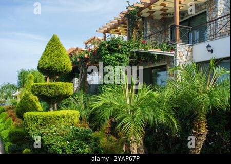 Une villa à flanc de colline présente une belle architecture entrelacée avec une verdure vibrante, avec des plantes tropicales bien entretenues et des haies artistiques und Banque D'Images