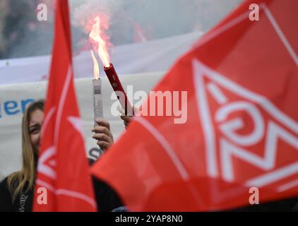 Ludwigsburg, Allemagne. 15 octobre 2024. Les travailleurs manifestent avec des fusées éclairantes le deuxième jour de négociations dans le cycle de négociations collectives pour l'industrie métallurgique et électrique avec des banderoles exigeant une augmentation de salaire de 7 pour cent. Crédit : Bernd Weißbrod/dpa/Alamy Live News Banque D'Images