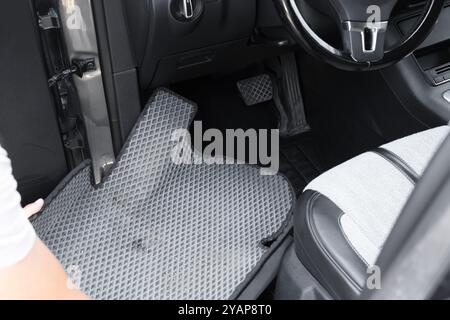 Homme prenant tapis de voiture en caoutchouc gris de l'auto, gros plan Banque D'Images