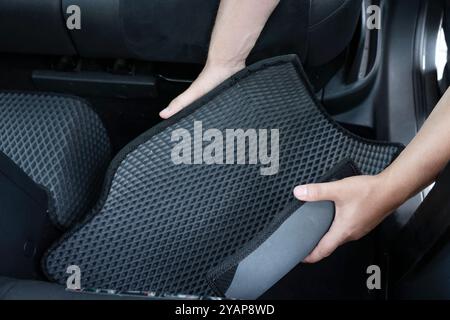 Homme prenant tapis de voiture en caoutchouc gris de l'auto, gros plan Banque D'Images