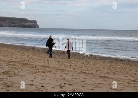 Deux personnes promenant leurs chiens sur Sandsend Beach, Yorkshire, Angleterre Banque D'Images