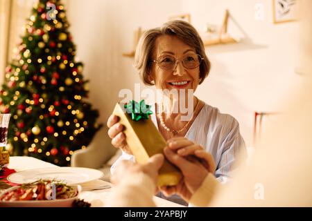 Un couple âgé heureux profite d'une célébration de Noël confortable, échangeant des cadeaux près de l'arbre décoré. Banque D'Images