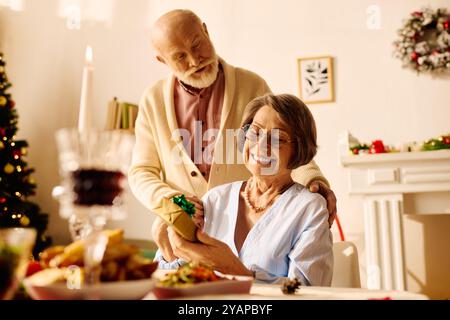 Un moment chaleureux en tant que couple senior partage des sourires et des cadeaux dans leur cadre confortable de maison de vacances. Banque D'Images