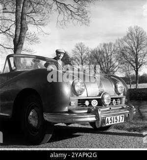 Un fier propriétaire de voiture dans les années 1950 Un homme dans sa voiture, une Austin A 90 Atlantic de 1950 avec le numéro d'immatriculation A51517. La voiture a été fabriquée par le constructeur automobile britannique Austin. Le modèle était initialement destiné à être vendu sur le marché américain. Il avait un corps ouvert, un cabriolet. La voiture avait un moteur à essence 4 cylindres, 4 vitesses et une propulsion arrière. La voiture avait trois phares. Ce propriétaire de voiture était membre de plusieurs associations automobiles internationales et leurs emblèmes sont montés sur le devant de la voiture. Anders Svahn ref SVA13 Banque D'Images