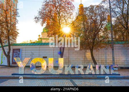 Kiev, Ukraine - 9 octobre 2024 : scène urbaine dynamique avec lettrage coloré qui lit 'YOUKRAINE' avec la lumière du soleil brille à travers les arbres dans un pict Banque D'Images