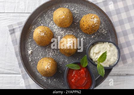 Risotto frits maison Arancini servi avec deux sauces en gros plan dans une assiette sur une table en bois. Vue horizontale de dessus Banque D'Images