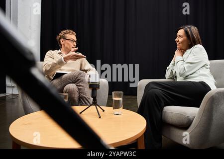 Un journaliste s'engage dans une interview réfléchie avec un spécialiste dans un studio, capturant des idées précieuses. Banque D'Images