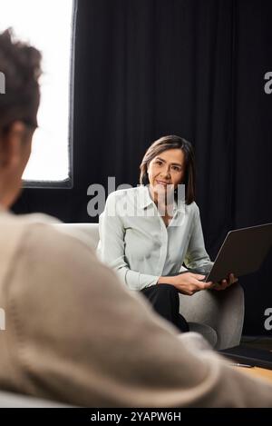 Un journaliste d'âge moyen s'engage dans une interview perspicace avec un spécialiste masculin dans une atmosphère chaleureuse. Banque D'Images