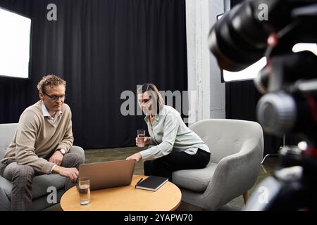 Un journaliste d'âge moyen s'entretient avec un spécialiste dans un studio professionnel, discutant de sujets importants. Banque D'Images