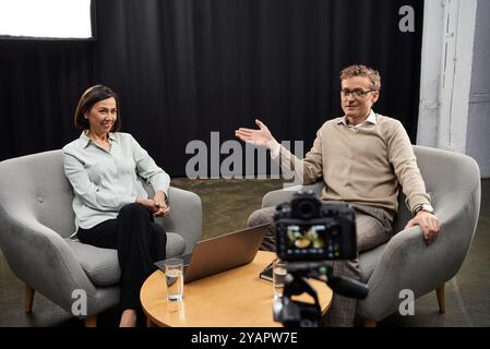 Une journaliste d’âge moyen engage un spécialiste dans une discussion réfléchie sur des sujets d’actualité. Banque D'Images