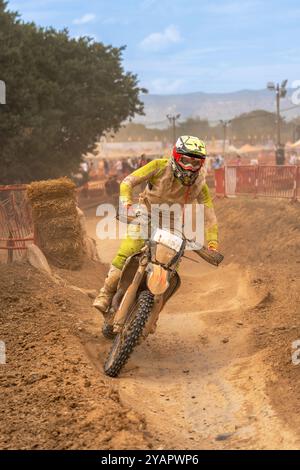 Pilote de motocross en action se préparant à prendre un virage serré sur un terrain poussiéreux en extérieur Banque D'Images