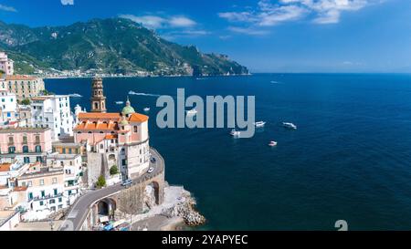 La vibrante côte amalfitaine brille sous un ciel bleu vif, où les bâtiments colorés s'accrochent aux falaises rocheuses, et les bateaux glissent en douceur à travers le shimme Banque D'Images