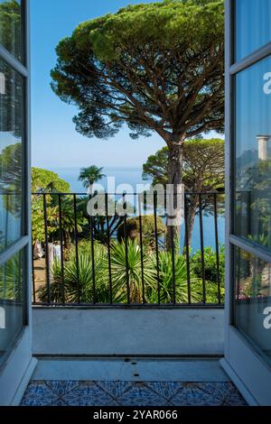 Le balcon baigné de soleil offre une vue fascinante sur la côte amalfitaine, entourée d'une végétation luxuriante et de palmiers vibrants. Une retraite parfaite pour profiter du Banque D'Images