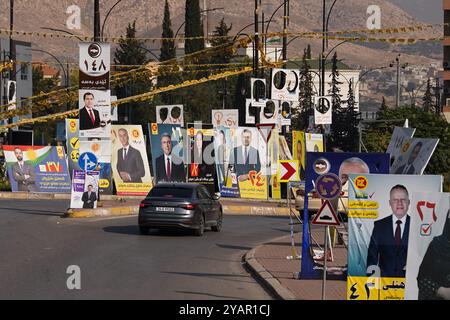 Duhok, Irak. 13 octobre 2024. Une voiture passe dans un rond-point devant les bannières électorales des candidats avant les élections du Parlement régional du Kurdistan dans la ville de Duhok, en Irak. (Photo de Ismael Adnan/SOPA images/SIPA USA) crédit : SIPA USA/Alamy Live News Banque D'Images