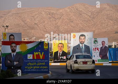 Duhok, Irak. 13 octobre 2024. Une voiture vue passer devant les bannières électorales des candidats avant les élections du Parlement régional du Kurdistan dans la ville de Duhok, en Irak. (Photo de Ismael Adnan/SOPA images/SIPA USA) crédit : SIPA USA/Alamy Live News Banque D'Images