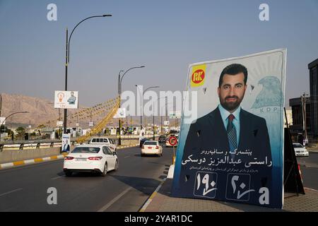 Duhok, Irak. 13 octobre 2024. Une voiture passe devant une bannière électorale du candidat du Parti démocratique du Kurdistan (PDK/PDK) avant les élections du Parlement régional du Kurdistan dans la ville de Duhok, en Irak. (Photo de Ismael Adnan/SOPA images/SIPA USA) crédit : SIPA USA/Alamy Live News Banque D'Images