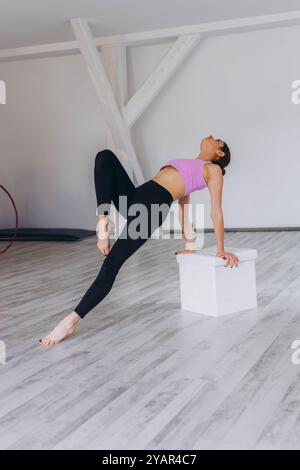 Fille gymnaste faisant de l'exercice difficile pour l'équilibre et la force sur la formation dans le gymnase. Photo de haute qualité Banque D'Images