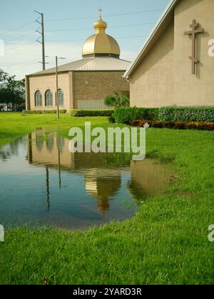 Bâtiment de l'église vue haute avec croix reflétant dans une piscine d'eau avec de l'herbe verte sur les côtés. Ciel bleu avec des nuages blancs. Pas de gens et de chambre Banque D'Images