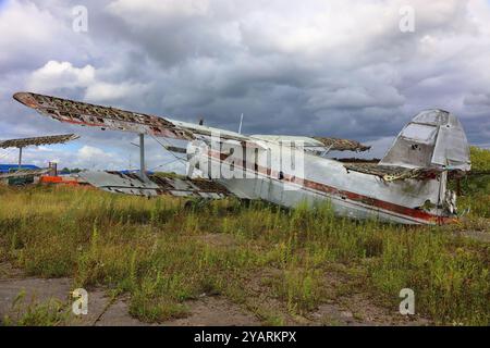 Vieil avion écrasé et abandonné debout dans le champ contre le ciel dramatique. Petit avion à hélice au cimetière de l'avion Banque D'Images