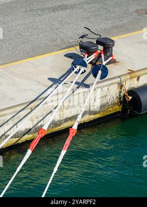 Cordes d'amarrage épaisses d'un navire tendu au poteau d'amarrage du quai en béton du port, corde pour immobiliser le navire, borne d'amarrage Banque D'Images