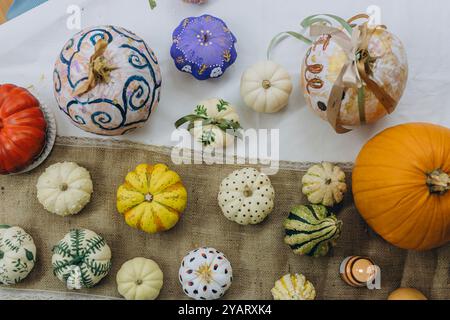 Enfants et adultes peignant des citrouilles pour Halloween, profitant d'une activité amusante et créative ensemble. Photo de haute qualité Banque D'Images