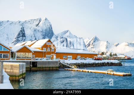 Sakrisoy village de pêcheurs et montagnes enneigées en hiver sur les îles Lofoten, Norvège. Paysage d'hiver avec des maisons traditionnelles de rorbu jaune sur pilotis Banque D'Images