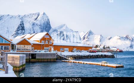 Sakrisoy village de pêcheurs et montagnes enneigées en hiver sur les îles Lofoten, Norvège. Paysage d'hiver avec des maisons traditionnelles de rorbu jaune sur pilotis Banque D'Images