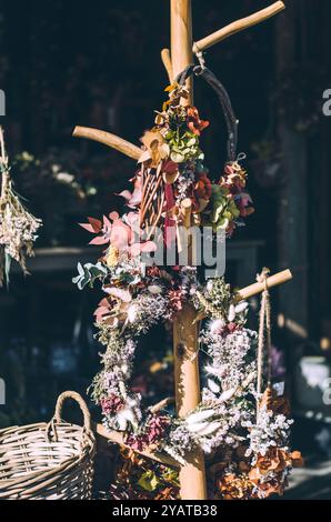 Couronnes artisanales avec fleurs séchées et eucalyptus suspendues sur un pilier en bois Banque D'Images