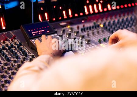 Ingénieur de suivi appuyant sur les faders et les boutons du pupitre de commande pour équilibrer les sons et ajouter des effets en post-production, créant ainsi de la nouvelle musique. Expert technique travaillant avec des curseurs en studio professionnel. Banque D'Images