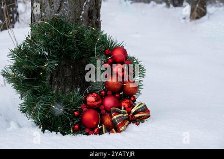 Couronne de Noël faite à la main à partir de décorations rouges. Préparation de vacances festives à l'extérieur par temps enneigé hivernal. Création durable de cadeaux de vacances responsables. Copier l'espace Banque D'Images