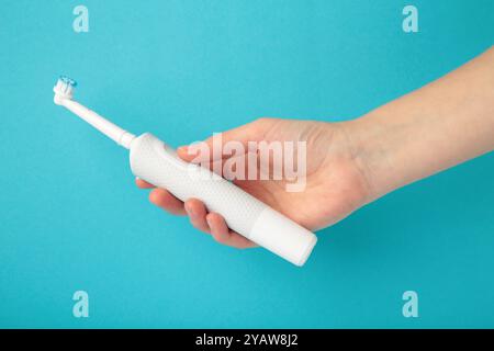 Femme tenant une brosse à dents électrique sur fond bleu. Vue de dessus Banque D'Images