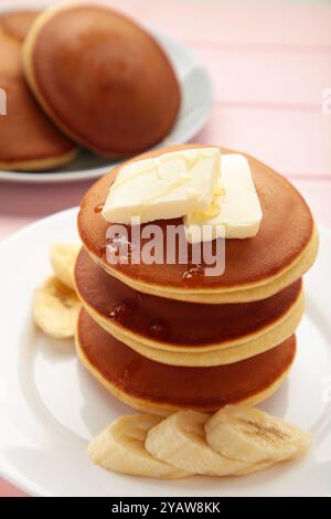 Assiette avec de délicieuses crêpes à la banane sur fond rose. Photo verticale. Vue de dessus Banque D'Images