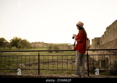 Voyager et passer-temps comme style de vie. Jeune femme appréciant les paysages marchant dans l'ancienne forteresse avec caméra. Copier l'espace Banque D'Images