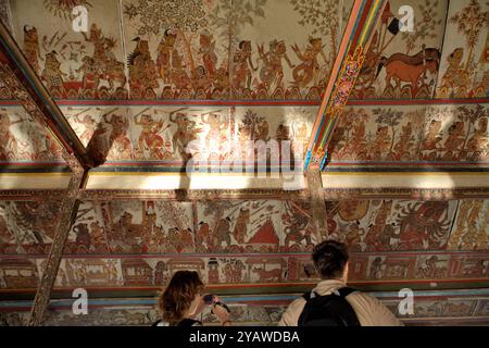 Touristes à Kertha Gosa, un ancien pavillon qui est décoré avec une vieille peinture de style kamasan sur ses plafonds, situé à Klungkung, Bali, Indonésie. Banque D'Images