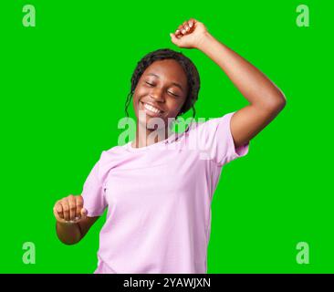 Une jeune femme avec des tresses exprime l'excitation avec un poing serré sur un fond vert vif Banque D'Images