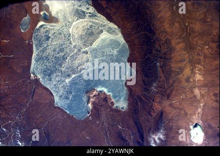 Cette image capture presque tout le Quinghai, le plus grand lac de Chine. Ce lac a une altitude de surface de 10 450 pieds ; remplissant partiellement l'un des bassins versants les plus fermés à l'est de l'Asie centrale. Il est situé dans la province du Quinghai sur le plateau tibétain du Quinghai. De petites villes de marché, dont Tianjun et Ganga, parsèment la périphérie du lac Quinghai. C'est ici, dans l'une des régions les plus ethniquement diversifiées de Chine, que les nomades tibétains encaissent leur bétail. Banque D'Images