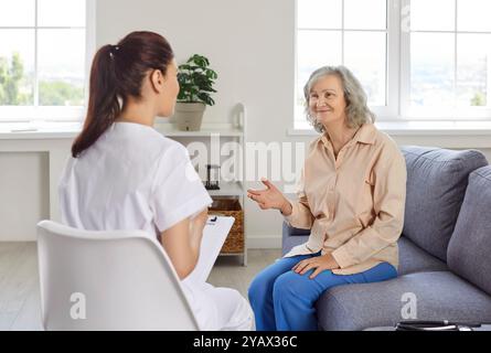 Médecin parlant à une patiente femme âgée heureuse et souriante lors d'une visite de contrôle à domicile Banque D'Images