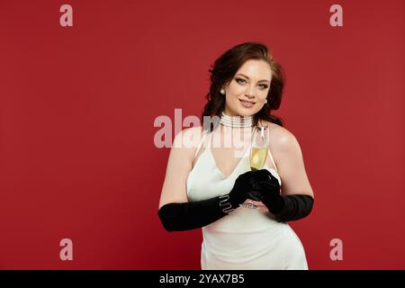 Une jeune femme dans une robe magnifique tient un verre de champagne, exsudant grâce et joie. Banque D'Images