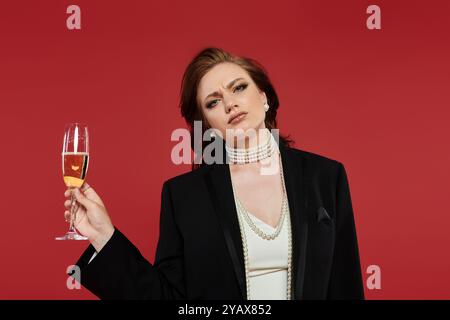 Cette femme élégante lève une coupe de champagne, exsudant confiance et style dans sa superbe tenue. Banque D'Images