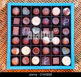 Boîte de chocolats belges de luxe coûteux située sur une table rustique en osier Banque D'Images