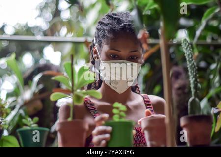 Jeune femme afro latine jardinière portant un masque facial Banque D'Images