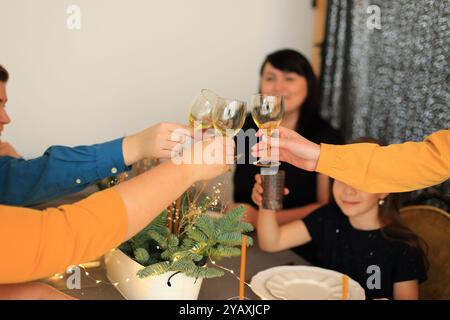 Bonne nouvelle année : griller au champagne. Plusieurs mains tenant des verres de champagne, levées sur un toast à une table du nouvel an magnifiquement dressée Banque D'Images