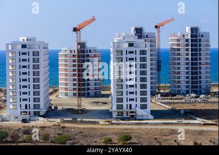 Plusieurs immeubles résidentiels de grande hauteur sont en construction le long de la côte, avec des grues surplombant et une vue dégagée sur l'océan à l'arrière-plan Banque D'Images